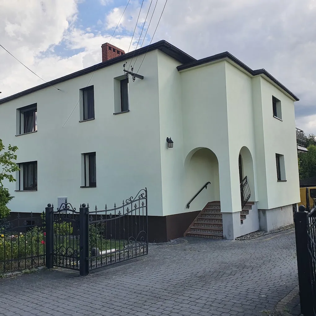 Odnowiona elewacja domu z kutą bramą wjazdową i tarasem wejściowym